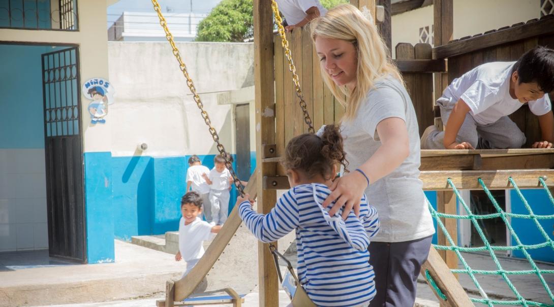 A Projects Abroad teenage community volunteer working in Ecuador pushes a child on the swing. A teenage volunteer working with children in Ecuador pushes a child on the swing.